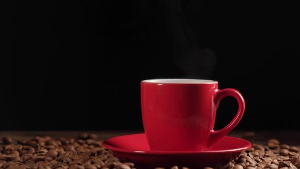 Червоний кухоль з гарячою парою ароматичної кави на купі цілих обсмажених кавових зерен . — стокове відео