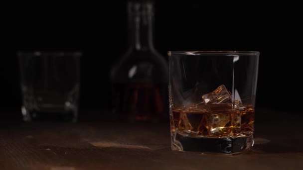 Vaso con whisky y hielo sobre mesa de madera. — Vídeos de Stock