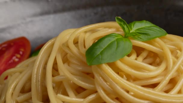 Pasta, espaguetis con cereza de tomate y albahaca en negro. — Vídeo de stock