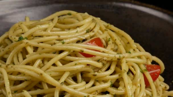 Паста, спагетті з песто і помідорами вишня в чорній мисці . — стокове відео