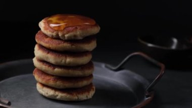 Koyu arkaplanda bal şurubu olan bir yığın krep..