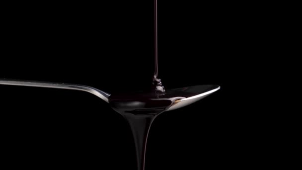 Chocolat liquide versé dans une cuillère sur fond noir. — Video