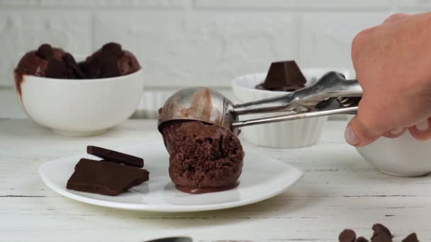 Una cucharada de helado de chocolate se pone en un plato — Vídeos de Stock