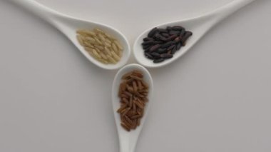 Çeşitli pirinçlerle dönen kaşıklar: siyah, basmati ve kahverengi pirinç. 