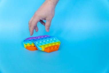 Renkli silikon anti-stres oyuncağı. Duyusal oyuncak. Mavi arka plana koy.