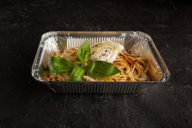 fresh pasta with cheese and mushroom sauce on a foil plate in the studio