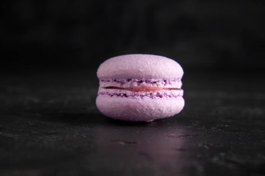 colored fresh macarons in studio on black background