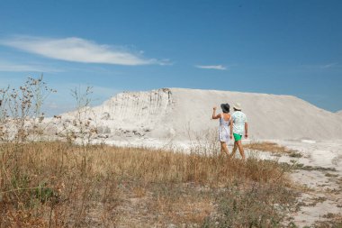 Kadın ve erkek yazın kum dağlarının arka planında poz verirler.