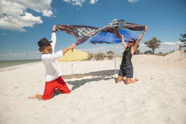 a man with a woman holding a blanket by the sea