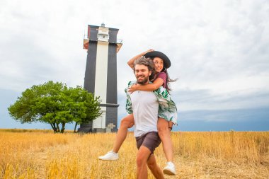 Bir adam yazın mavi gökyüzünün arka planında bir kadını taşır.