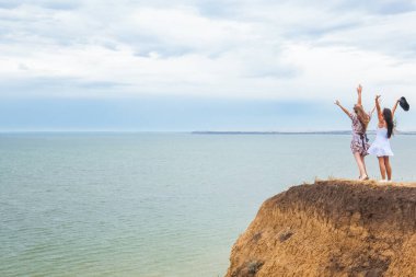 Yazın ıssız bir yerde uçurumun kenarında güzel bir manzaranın tadını çıkaran iki kadın.
