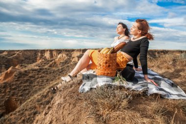 Yazın ıssız bir yerde uçurumun kenarında güzel bir manzaranın tadını çıkaran iki kadın.