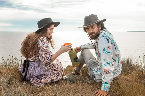 男と女は夏に丘の上にある魔法瓶から注ぐコーヒーを飲む ロイヤリティフリーのストック画像