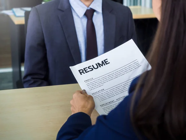 Resume or CV paper in employer \'s hand and review the applicant profile. Businesswoman, HR reading resume of young man in suit in office. Job interview and employment concept.