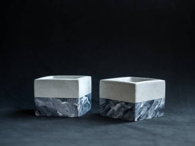 Karanlık arka planda, fotokopi alanı olan iki boş, modern, geometrik beton ekici. Beton kaplar, küp şeklinde..