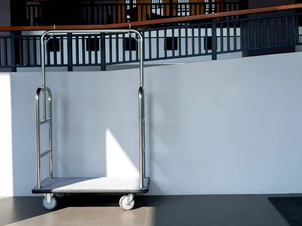 Empty hotel luggage trolley cart in front of white wall background with copy space.