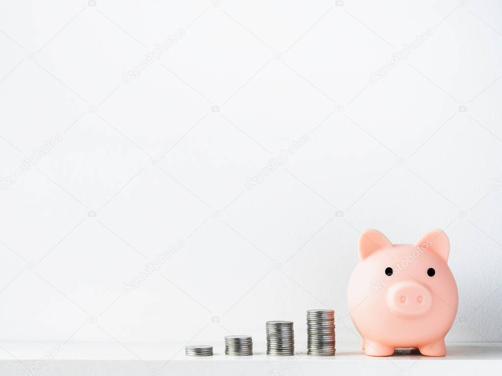 Cute piggy bank, pink color, front view with stacks of coins arrange as a graph isolated on white background with copy space. Saving money, Investment and finance concept.