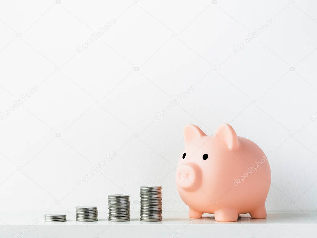 Cute piggy bank, pink color with stacks of coins arrange as a graph isolated on white background with copy space. Saving money, Investment and finance concept.
