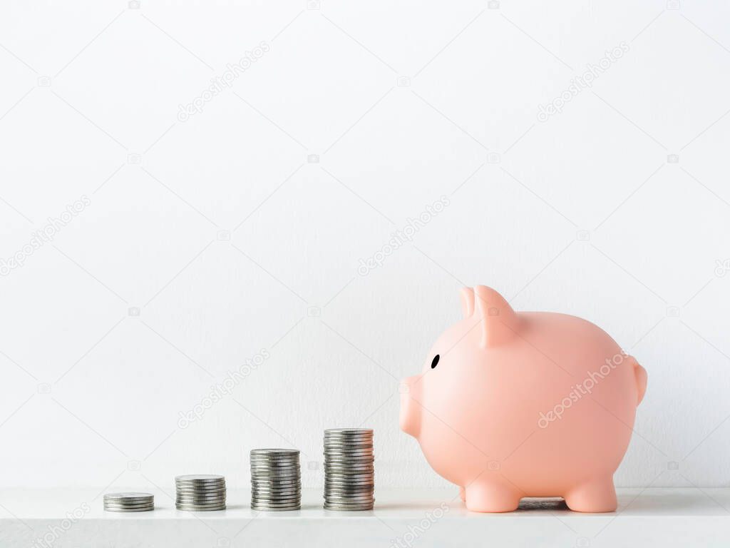Cute piggy bank, pink color, side view with stacks of coins arrange as a graph isolated on white background with copy space. Saving money, Investment and finance concept.