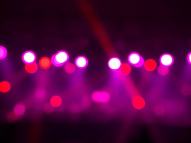 Sahnenin arka planında bulanık sahne ışığı, renkli ışın ve lazer ışınları. Etkisiz hale getirilmiş eğlence gösterisi ışıklandırması.