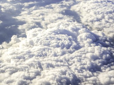 Bulutun üstünde, uçak penceresinden inanılmaz bir gökyüzü manzarası. Kabarık bulutlu arkaplan ile güzel bulutlu manzara.