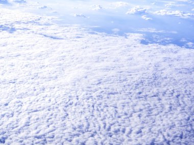 Bulutun üstünde, uçak penceresinden inanılmaz bir gökyüzü manzarası. Kabarık bulutlu ve mavi gökyüzü arkaplanlı güzel bulutlu manzara.