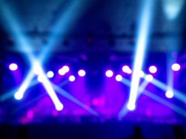 Sahnenin arka planında bulanık sahne ışığı, renkli ışın ve lazer ışınları. Etkisiz hale getirilmiş eğlence gösterisi ışıklandırması.