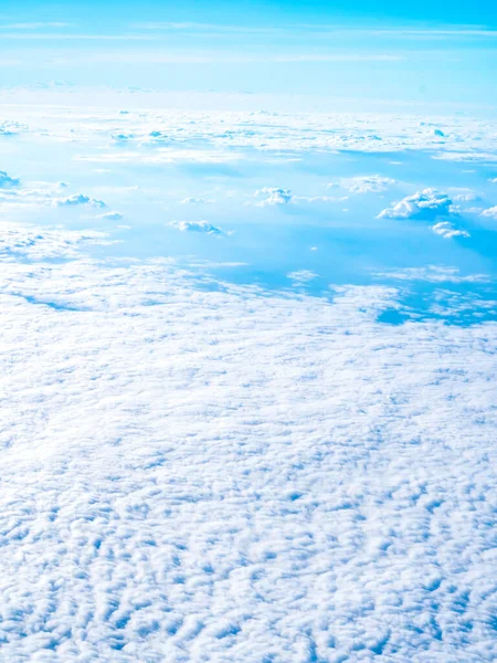 Above the cloud, amazing sky view from airplane window. Beautiful cloudscape with fluffy cloudy and blue sky background, vertical style.