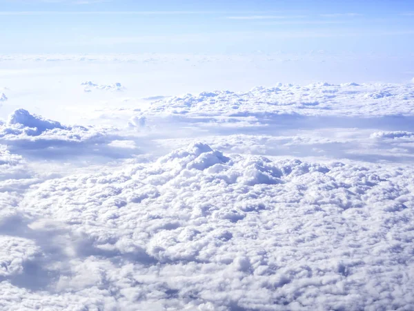 Above the cloud, amazing sky view from airplane window. Beautiful cloudscape with fluffy cloudy and blue sky background.