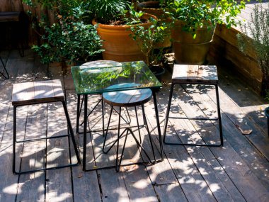 Boş cam masa, tahta sandalyeler, tahta bacaklar, ahşap zemin, açık yeşil bahçe..