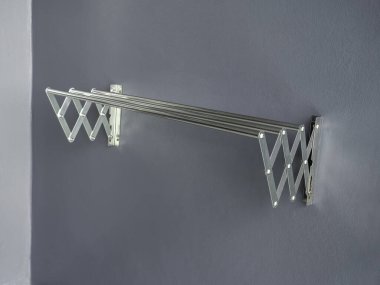 Aluminium folding clothes drying rack on the wall. Empty stainless steel wall mounted laundry folding towel drying rack with copy space. clipart