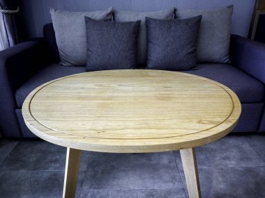 Yuvarlak ahşap masa. Boş kahverengi yuvarlak ahşap masa, otel odasındaki mavi gri koltuğun yanında..