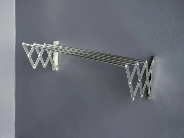 Aluminium folding clothes drying rack on the wall. Empty stainless steel wall mounted laundry folding towel drying rack with copy space.