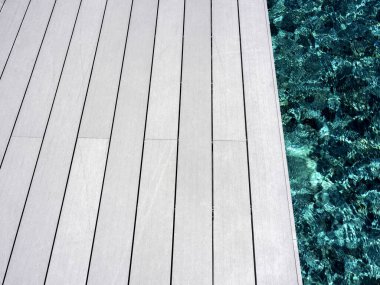 Havuz kenarında beyaz, temiz ahşap döşeme. Yüzme havuzunun yakınındaki ahşap zeminde boş bir alan, yaz dönemi konsepti..