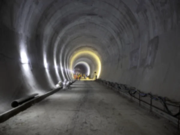 Blurred background of railway tunnel construction site. Blurry straight circular concrete railway tunnel with lighting.