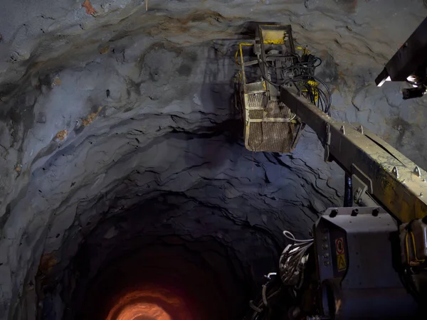 Tunnel excavator working in dark railway tunnel construction site background.