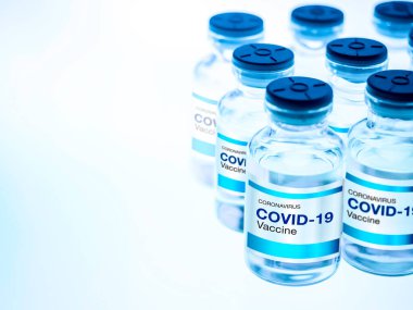 Covid-19 aşısı. Modern etiket Covid-19 şişedeki aşılar ışık masasını aydınlatan mavi tonlu bir laboratuvar. Bir koronavirüs aşısı geliştirilmesi ve oluşturulması.