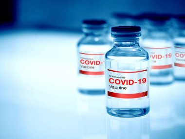 Covid-19 aşısı. Modern etiket Covid-19 aşı şişe şişeleri üzerinde ışık masası üzerinde fotokopi alanı olan bir araştırma laboratuarında, mavi tonda. Bir koronavirüs aşısı geliştirilmesi ve oluşturulması.