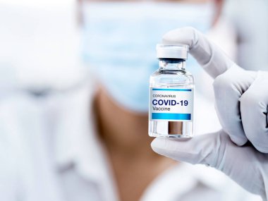 Covid-19 aşısı. Laboratuvarda eldiven takan bir bilim adamı ya da doktorun şişe şişesi üzerindeki modern Covid-19 aşısını kapatın. Coronavirüs aşısının geliştirilmesi ve yaratılması.