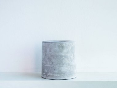 Beyaz arka planda izole edilmiş beyaz ahşap bir raftaki boş, yuvarlak beton saksı. Kaktüs, sulu bitkiler ya da çiçekler için küçük çimento ekicisi..