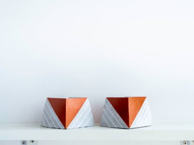 Boş beton kaplar, beyaz ahşap bir rafta piramit şeklinde beyaz duvar zemininde fotokopi alanı olan. İki eşsiz bakır renkli çimento ekicisi..