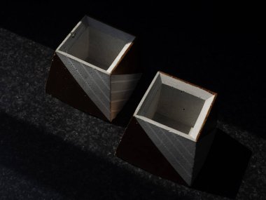 Boş beton kaplar, piramit şeklinde koyu arkaplan, üst manzara. İki eşsiz bakır renkli çimento ekicisi..