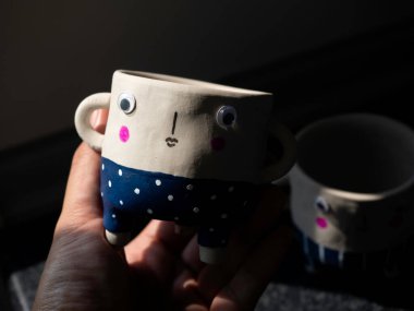 Şirin yüz seramik saksısı elinde. Yakın plan küçük modern DIY çimento ekicileri moda dekorasyonu..