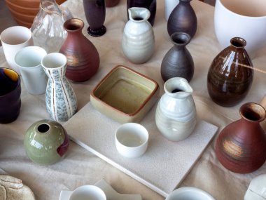 Beyaz bembeyaz kumaşlı, üst manzaralı çeşitli renkli seramik vazolar. Boş seramik vazo arkaplanı.