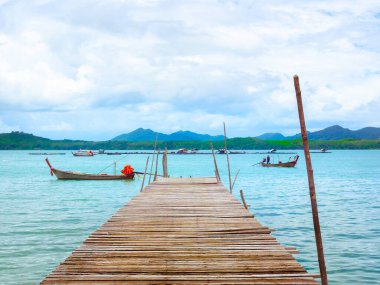 Güzel deniz manzaralı yaz arkaplanı. Tayland 'da güneşli bir günde denizde ve gökyüzünde yerel balıkçı teknesiyle boş tahta köprüyü kapatın..