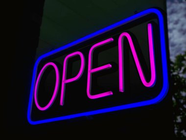 Barın ya da kafenin girişinde açık neon levha, koyu arkaplan, açık pembe metin mavi kare işareti, iş tabelası için 