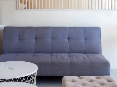 Modern beyaz yuvarlak masa yakınındaki boş koyu gri kumaş kanepe ve oturma odasındaki beyaz duvarda kare koltuk, temiz ve minimal dekorasyon iç dekorasyonlu rahat mobilyalar..