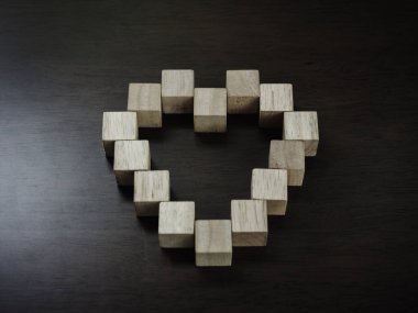 Koyu ahşap arka planda kalp şeklinde ahşap bloklar, üst manzara. Aşk ve birlikte yaşam kavramı.