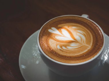 Latte art kahve fincanı. Sütlü kahvenin kapuçinosunu kapuçinoyla kaplayın. Güzel bir ışık ve gölge, üst manzara..