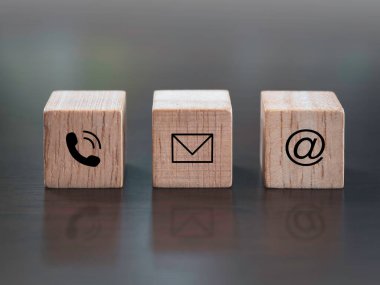 Bizimle irtibata geçin, pazarlama ve bilgi kavramı. Telefon, adres ve e-posta simgesini koyu ahşap arka plandaki tahta küp bloğunda kapat.